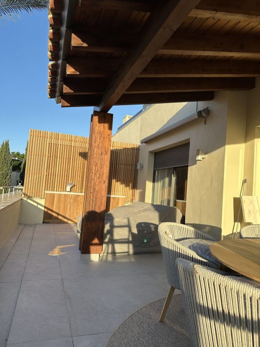 Terraza terminada del piso de lujo, con el techo de madera y el mobiliario puesto