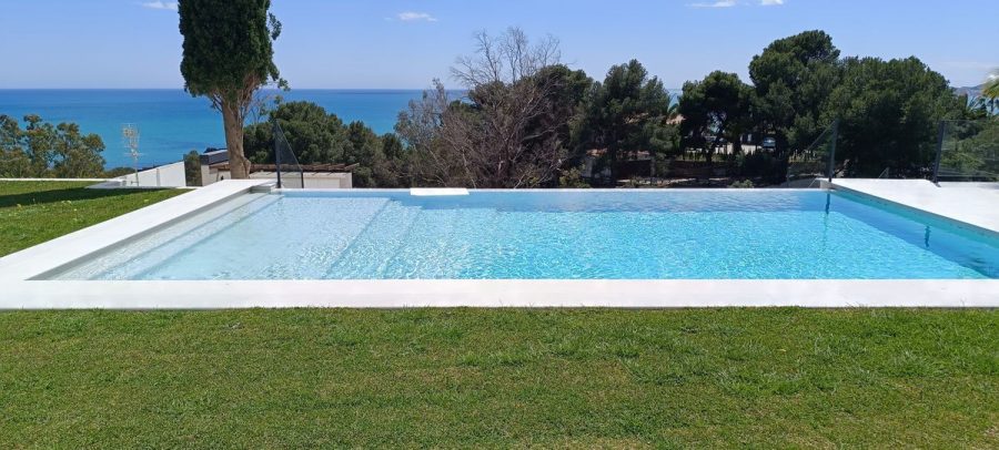 Piscina y jardín del chalet, con el mar al fondo