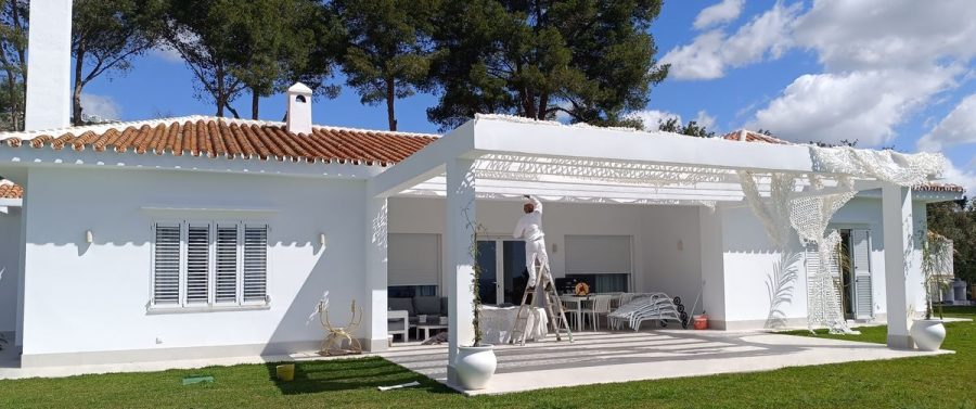 Operario en la escalera junto a la pérgola, visto desde el jardín